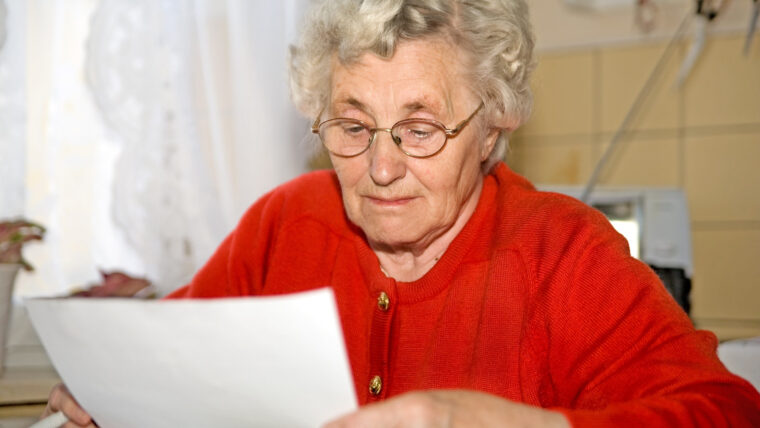 Oma liest Brief mit Mieterhöhung.